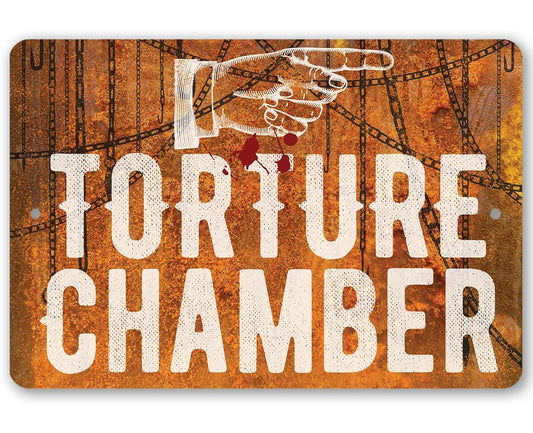 Rusty metal sign reading TORTURE CHAMBER with top hanging grommets